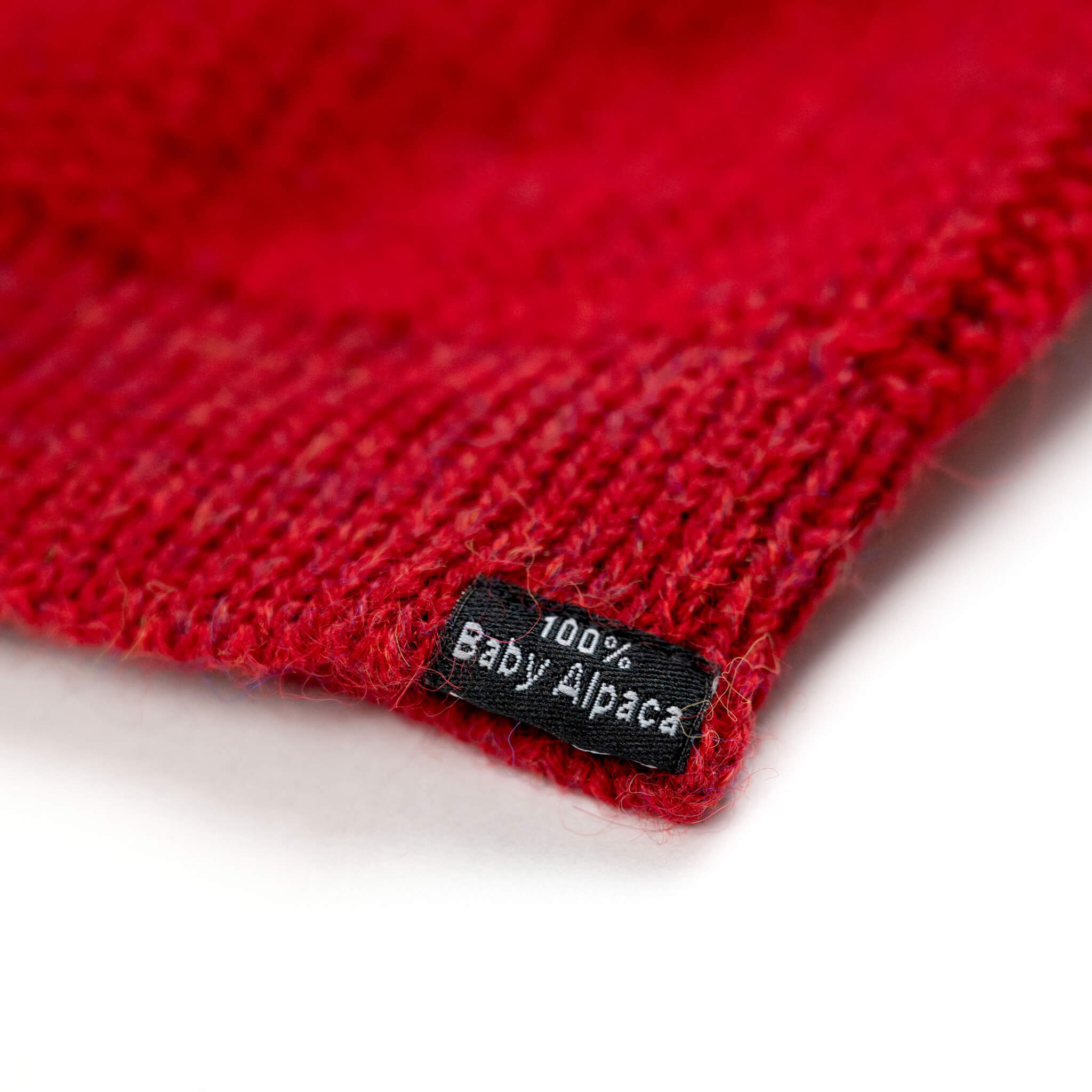Nahaufnahme Etikett 100% Babyalpaka auf rotem Textil