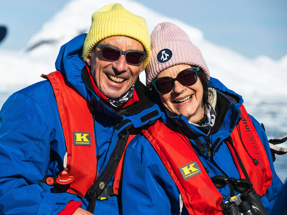 Reinhard und Solveig glücklich mit bunten Mützen auf ihrer Antarktisexpedition mit Rettungsweste