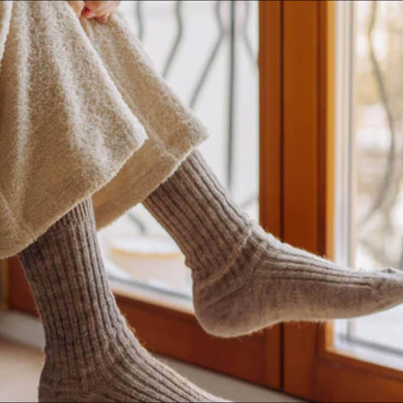 Frau trägt wärmsten Socken aus Alpakawolle gemütlich zuhause