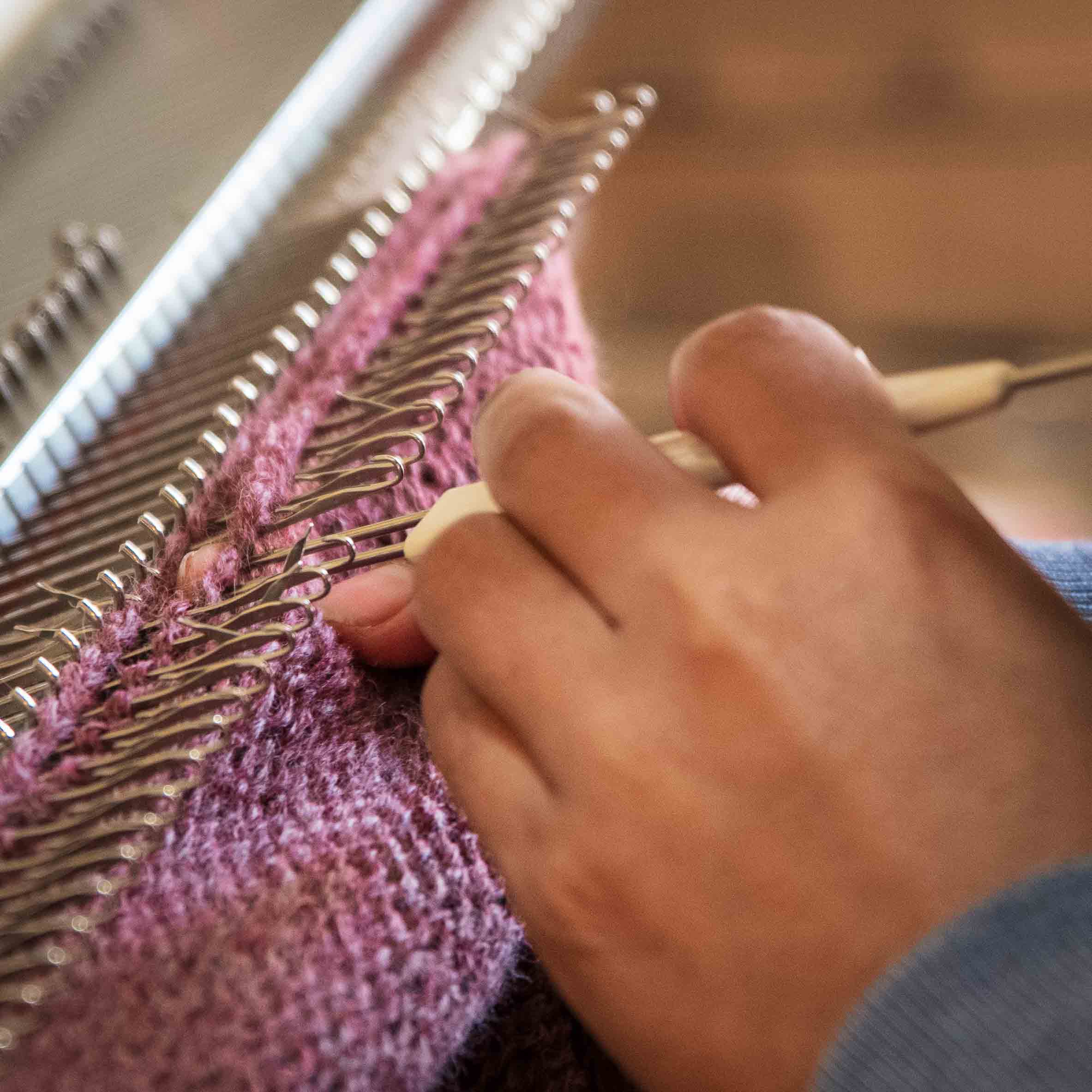 Nahaufnahme einer Hand, die das Kleidungsstück aus Alpakawolle kettelt