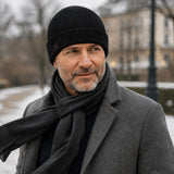 Mann mit grauem Bart trägt die Winddichte Alpaka Beanie Mütze in schwarz zu Mantel an kaltem Wintertag mit Wind