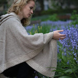 Frau mit elegantem Luz Alpaka Poncho mit Kapuze von Alpakin berührt Blumen