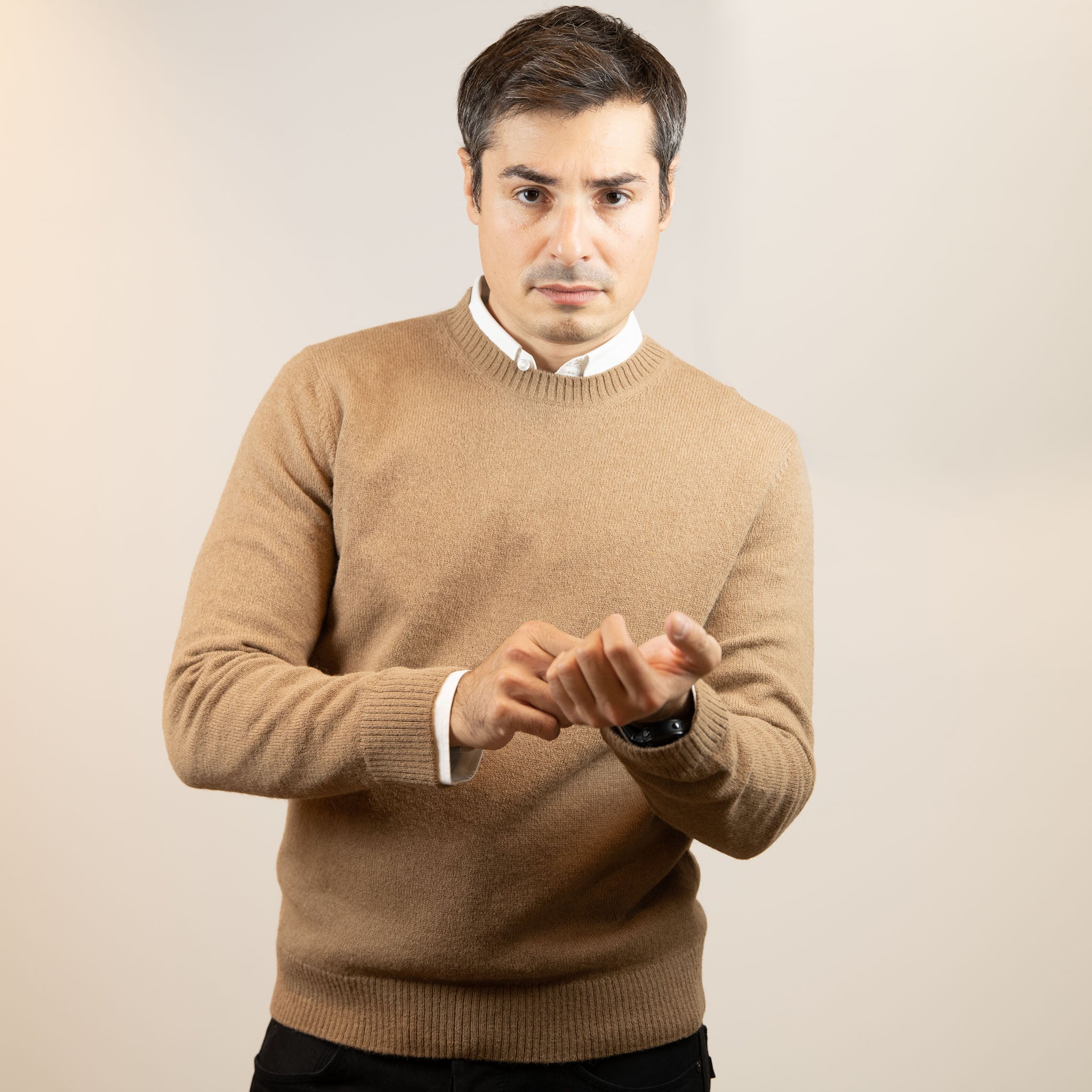 Mann mit Alpaka Naturfarbe Pullover in hellbraun blickt selbstbewusst und richtet sich die Uhr