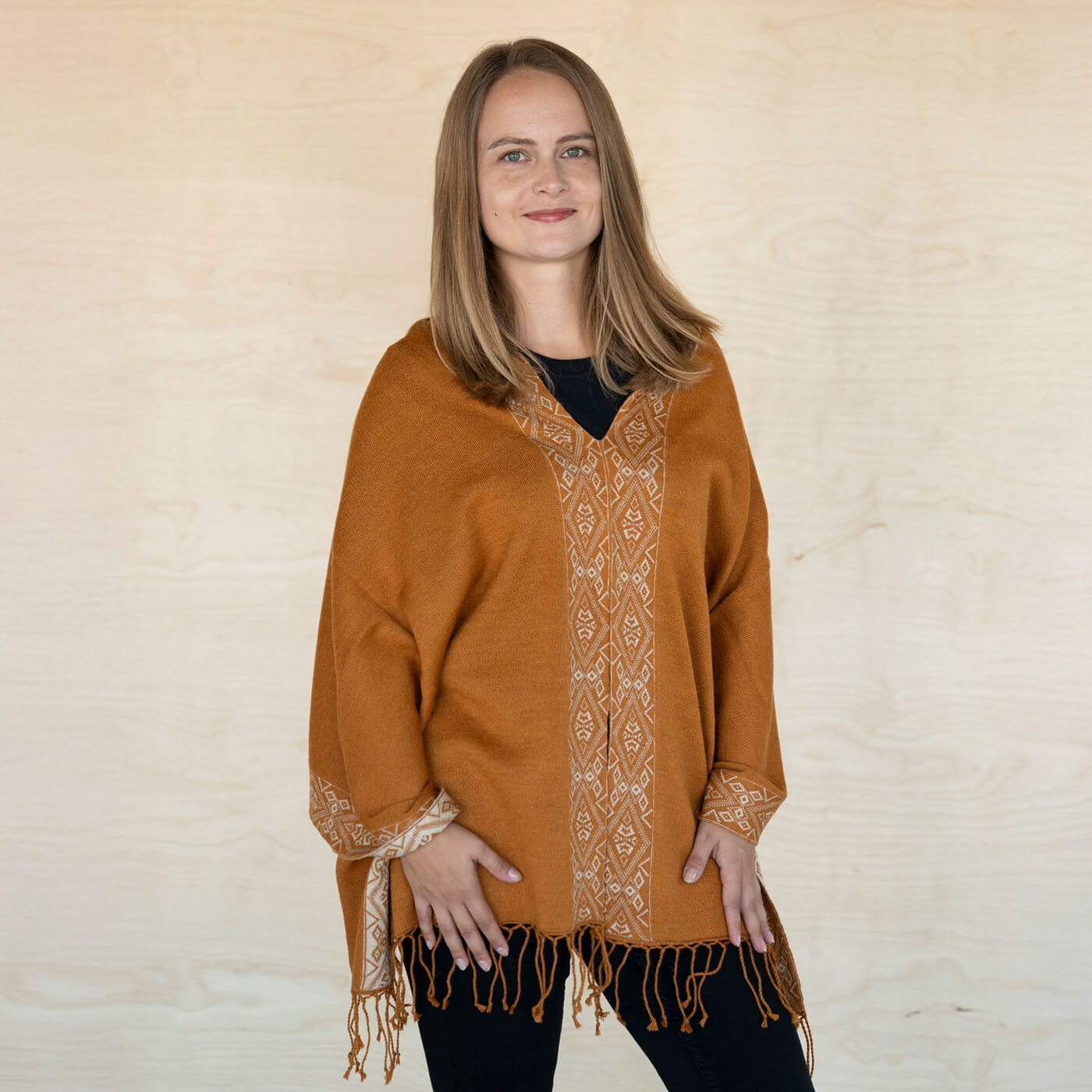 Frontalaufnahme einer blonden Frau, die den Flor Alpaka Poncho Schal in Kamel trägt