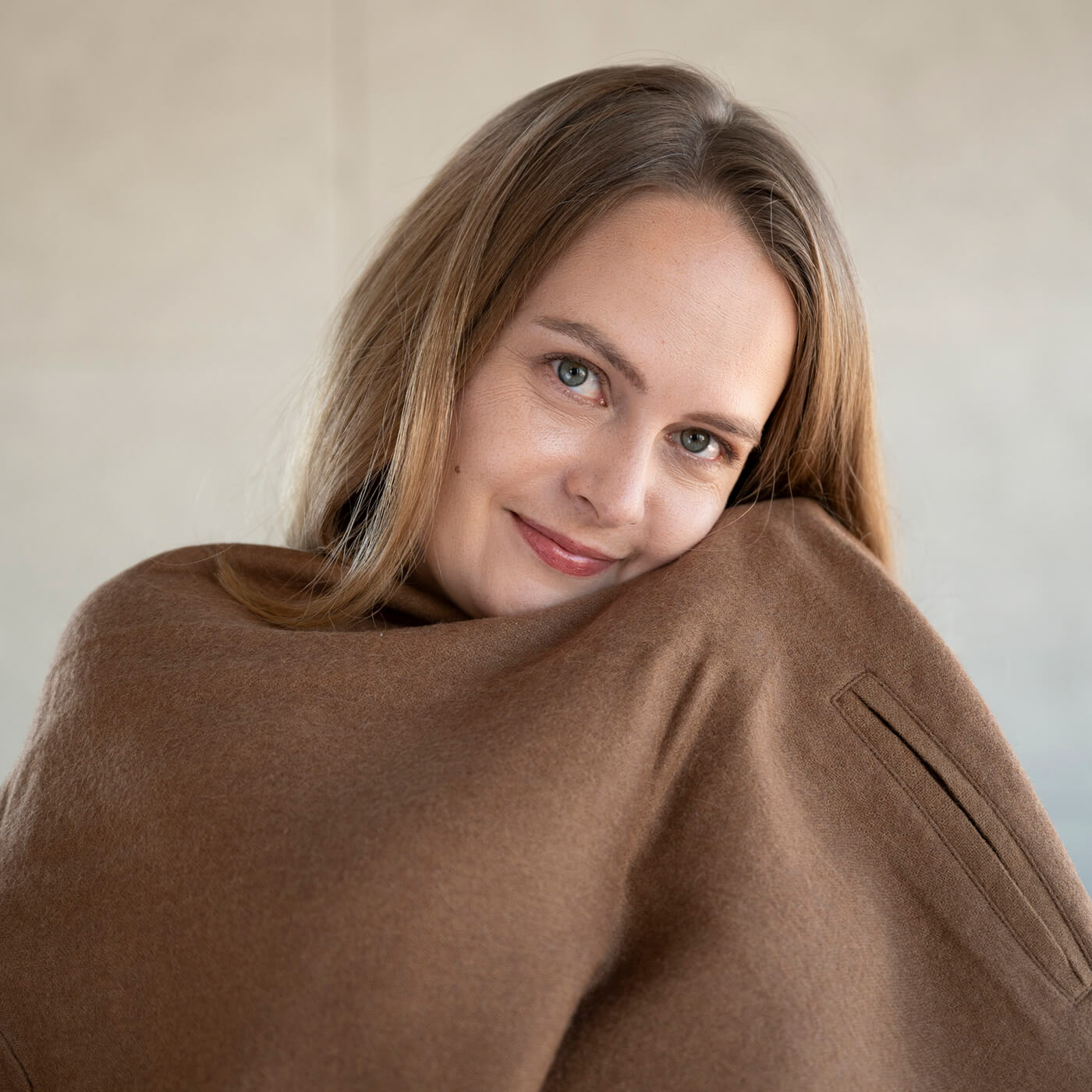Frau kuschelt sich in ihren weichen Oro Poncho Mantel aus feinster Alpakawolle