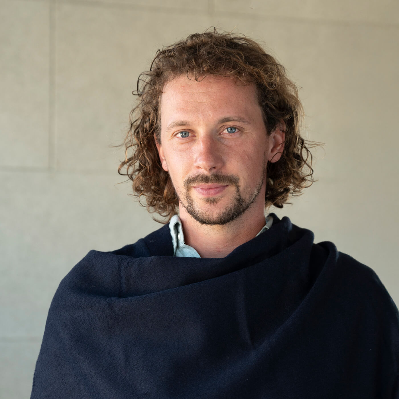 Portraitaufnahme Mann mit eleganter Alpaka Poncho Jacke in dunkelblau