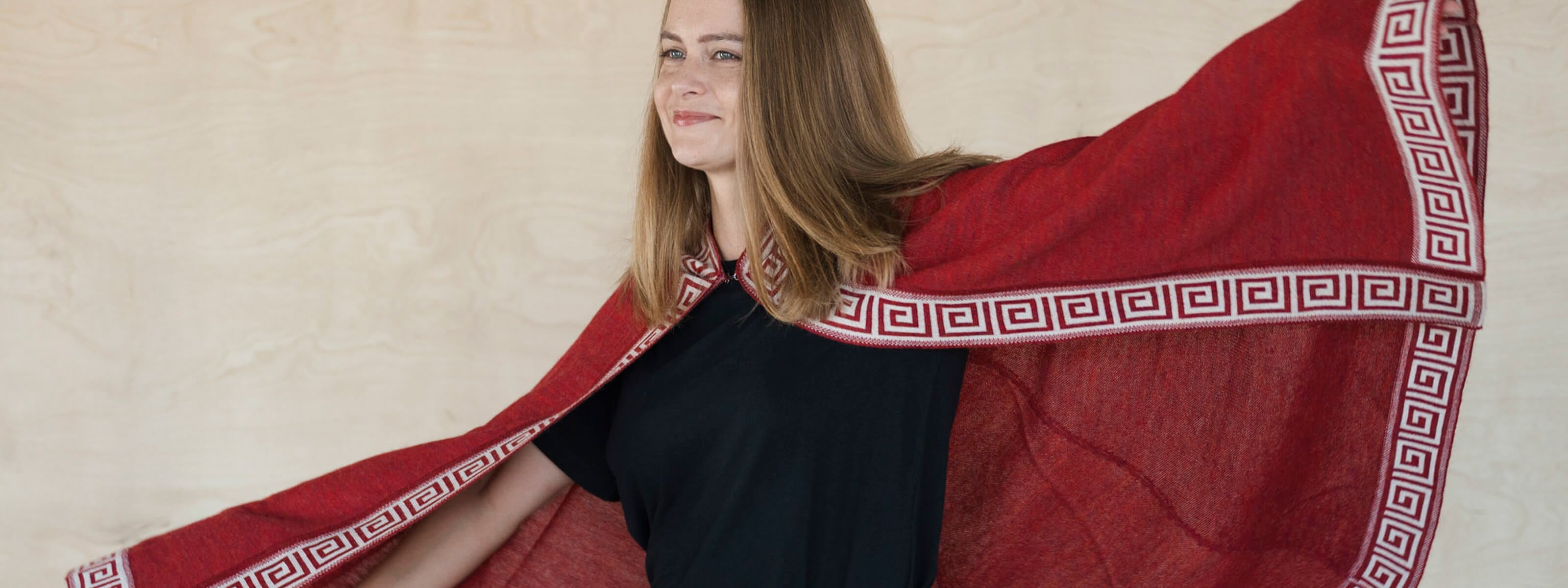 Frau bewegt sich frei mit dem Alpaka Poncho Luz in rot
