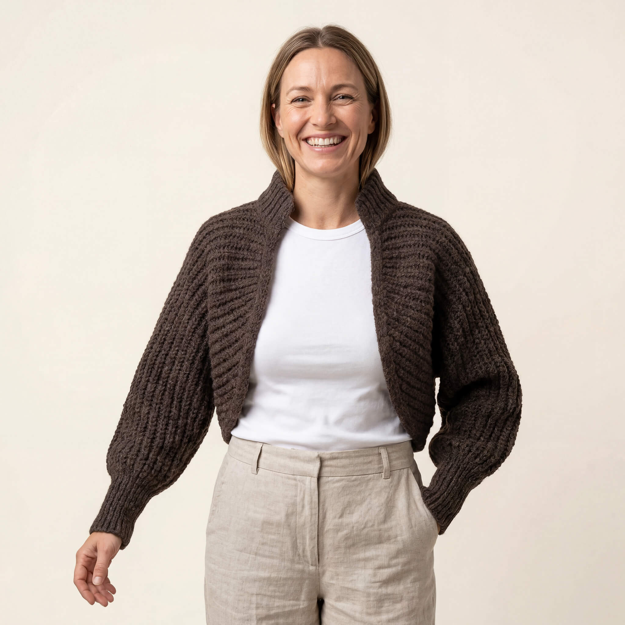 Dunkelblonde Frau genießt die Bewegungsfreiheit der Killa Strickjacke, die vorne offen ist