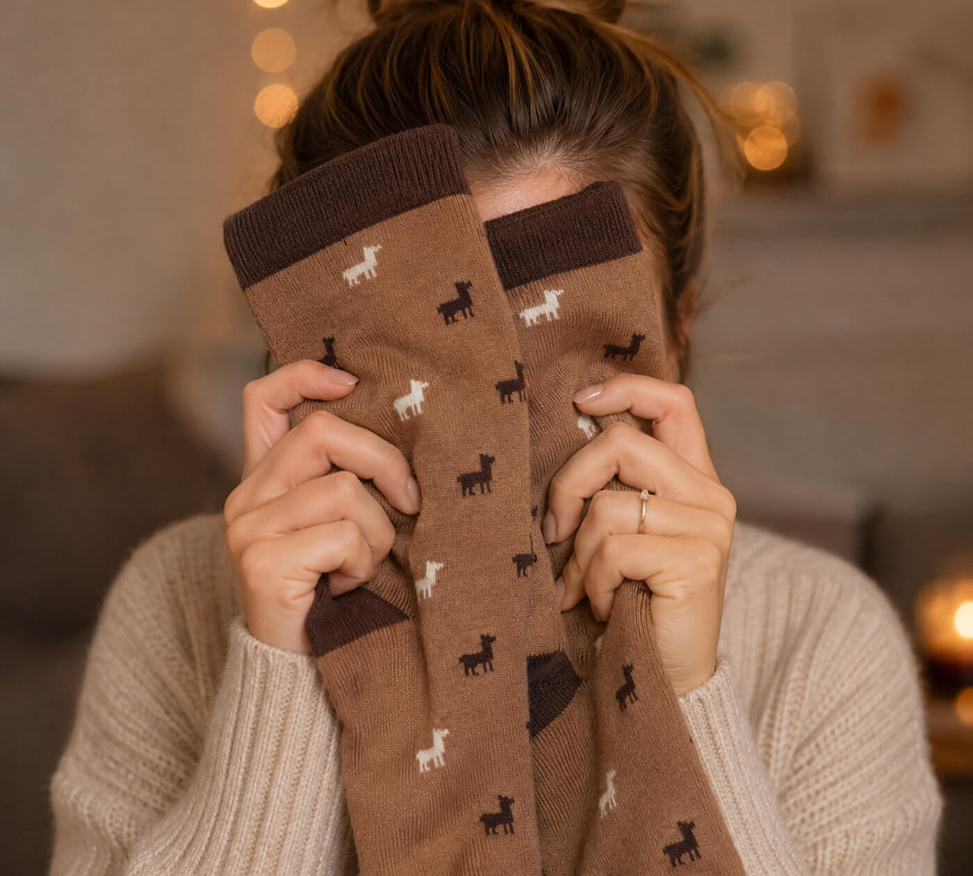 Frau hält sich die kuscheligen Socken mit Alpaka Motiv vors Gesicht