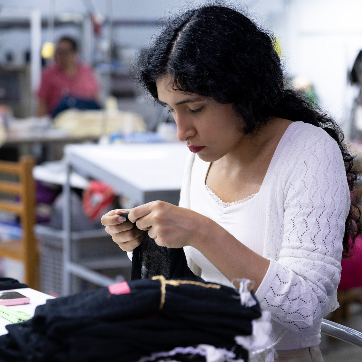 Frau in der Alpakin Manufaktur prüft ein Textil genau