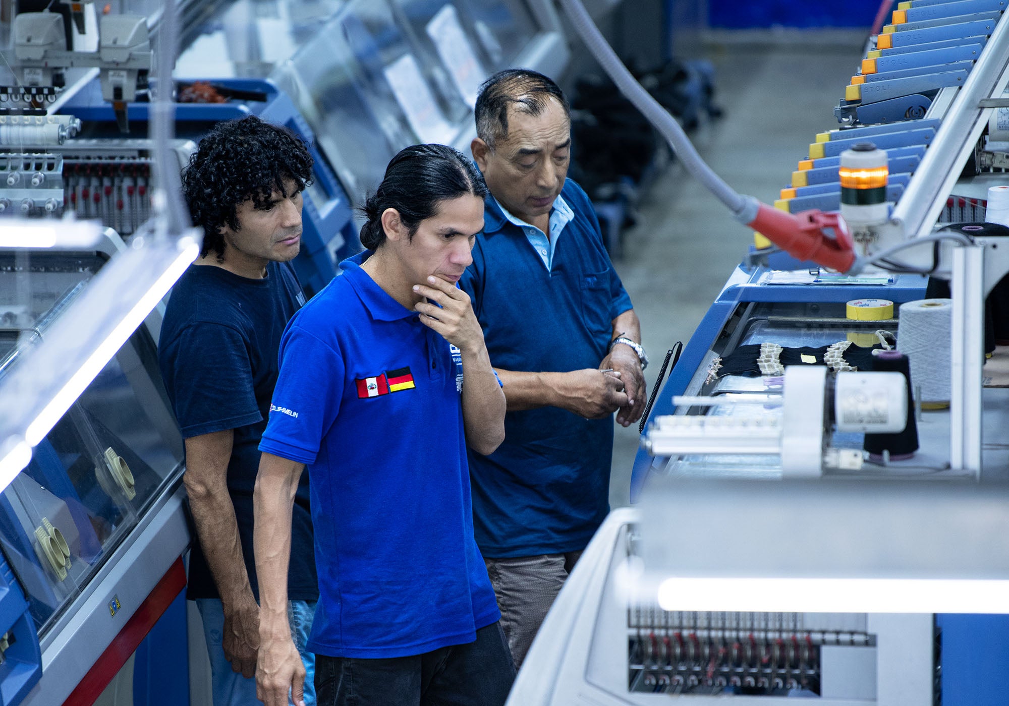Peruaner in unserer Manufaktur in Lima sehen sich die Maschinen an und sind nachdenklich