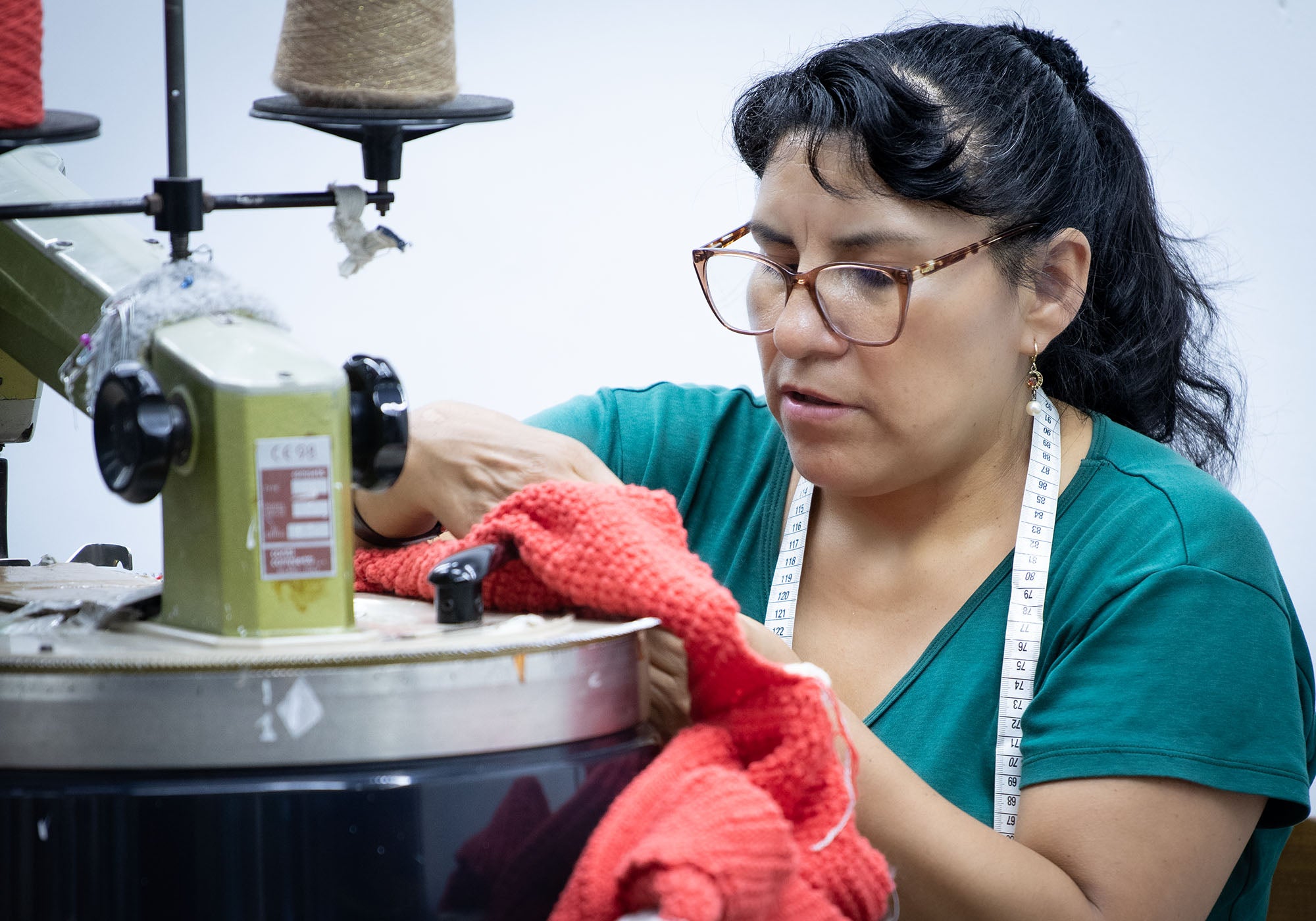 Peruanerin mit rotem Textil an der Maschine in unserer kleinen Manufaktur in Lima