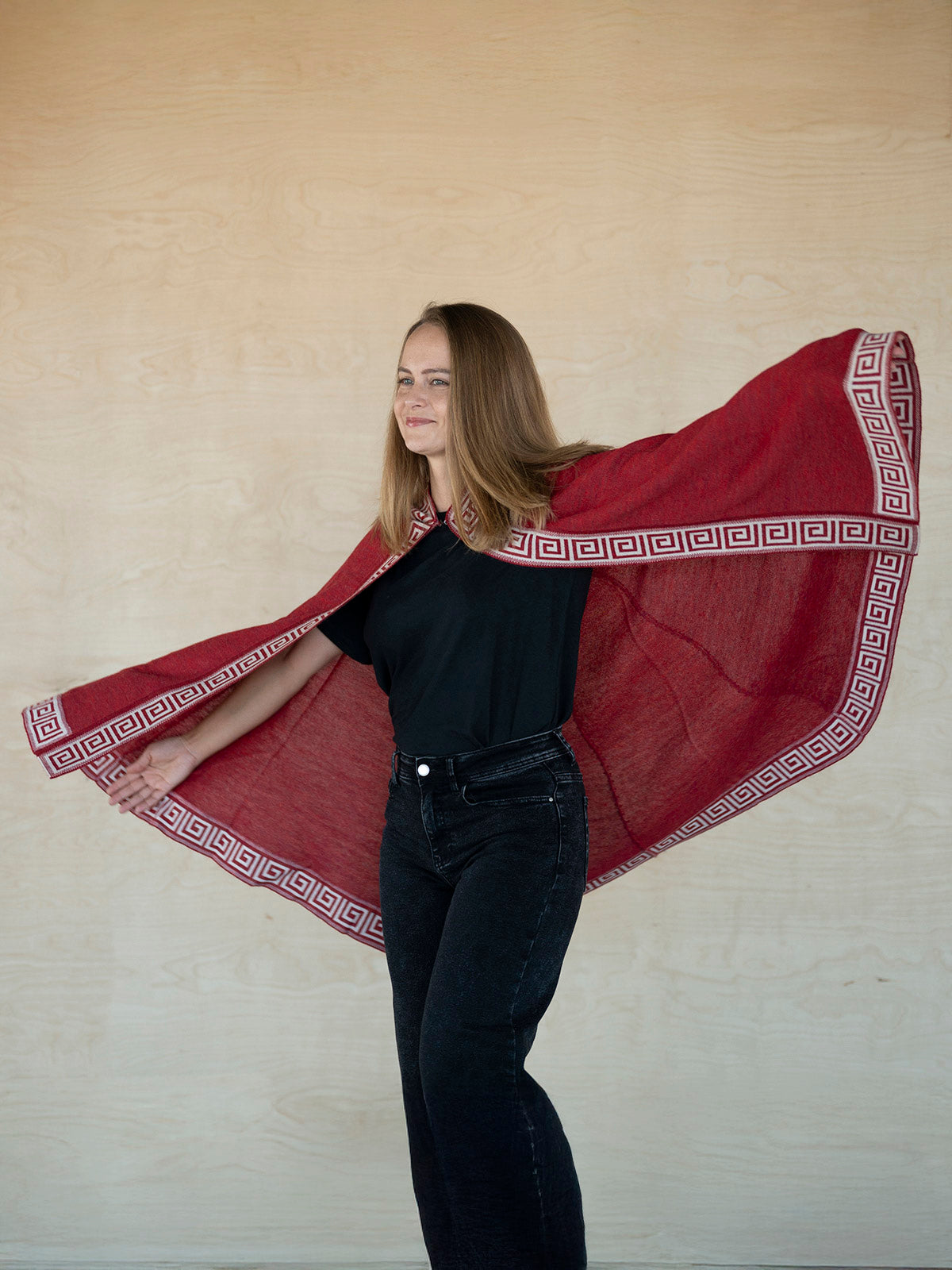 Frau bewegt sich frei mit dem Alpaka Poncho Luz in rot - Mobile Version