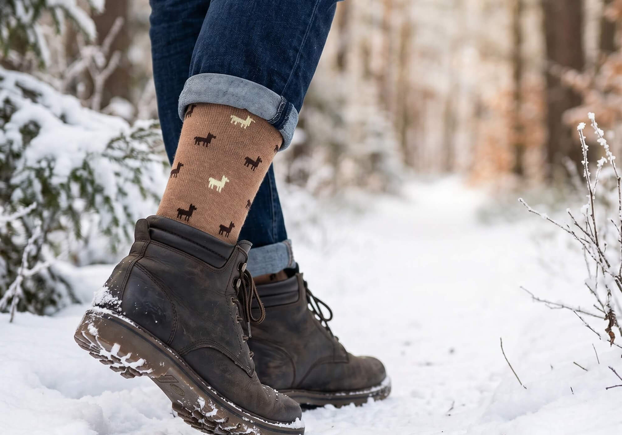 Warme Socken mit Alpaka Motiv getragen in winterlichem Wald in Stiefeln