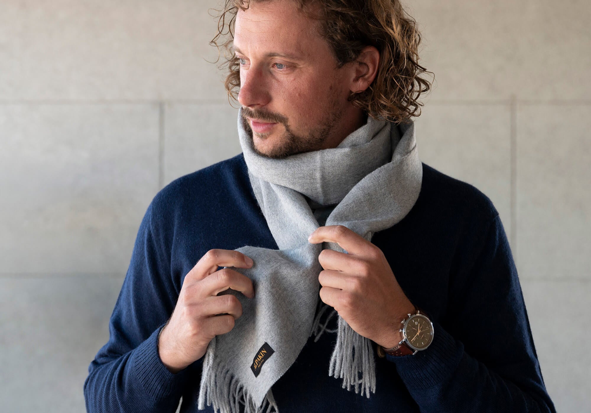 Mann trägt den Katari Alpaka Troyer in dunkelblau in Kombination mit einem Babyalpaka Schal in Naturfarbe hellgrau