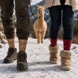 Paar trägt Socken mit Alpaka Motiv auf winterlicher Alpaka Wanderung