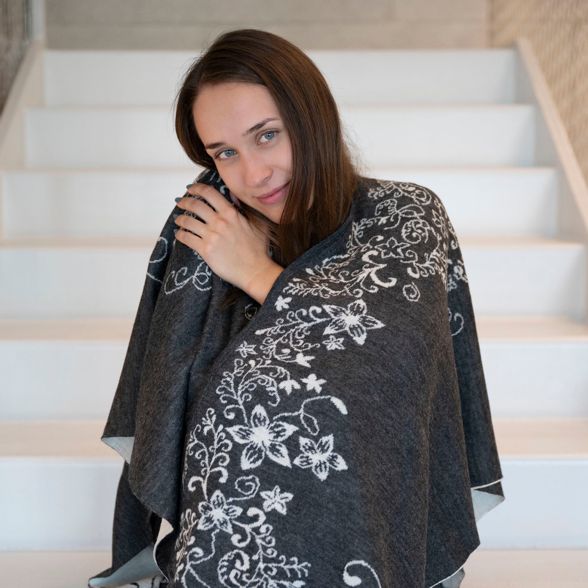 Frau hüllt sich in ihren kuschelweichen Babyalpaka Wendeponcho von Alpakin, der weich wie Kaschmir ist