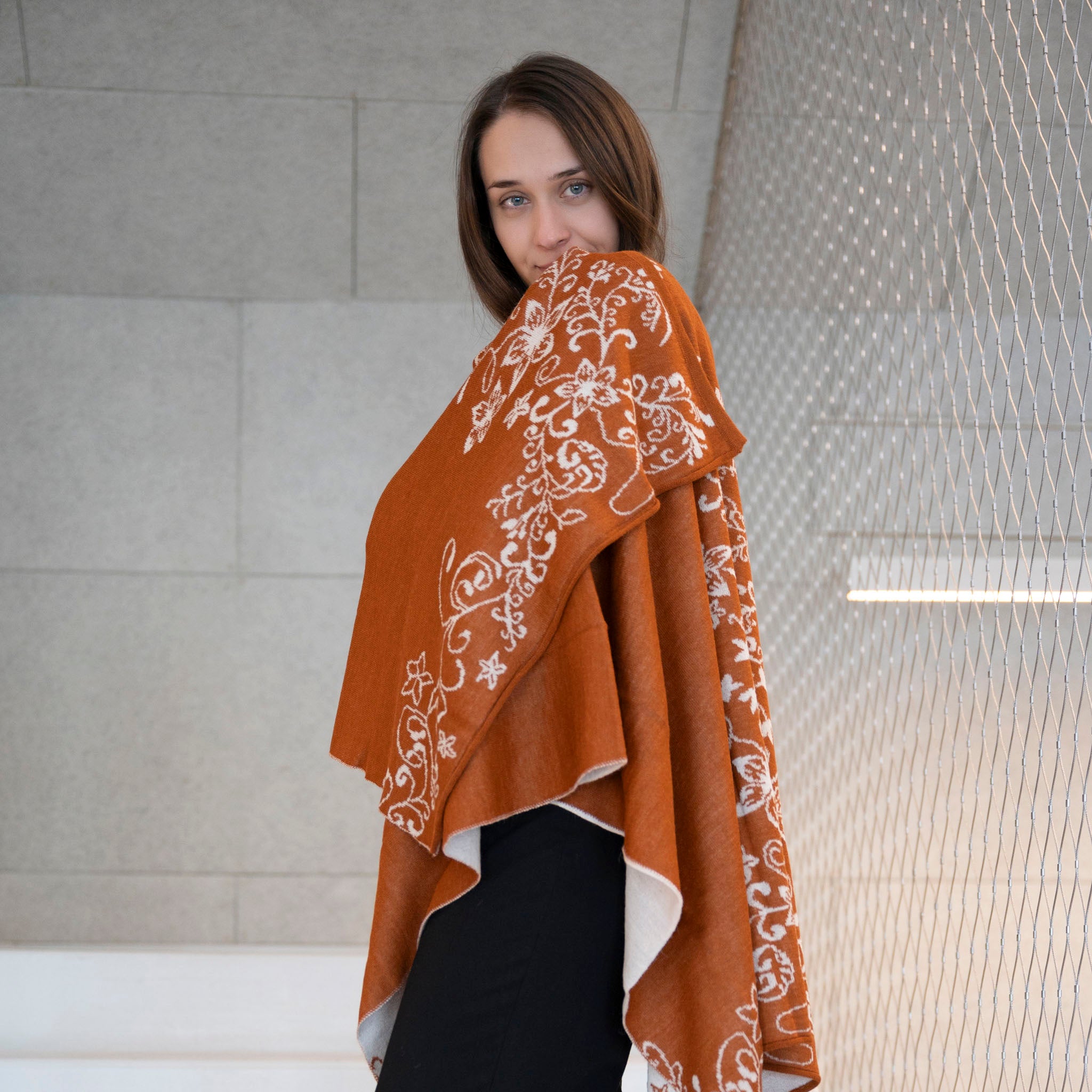 Seitliche Ansicht einer Frau mit Tamaya Alpaka Wendeponcho von Alpakin in dunkelorange